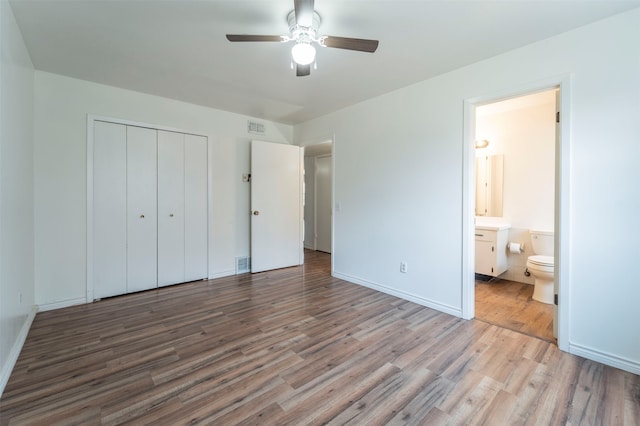 unfurnished bedroom with ceiling fan, light hardwood / wood-style flooring, ensuite bathroom, and a closet