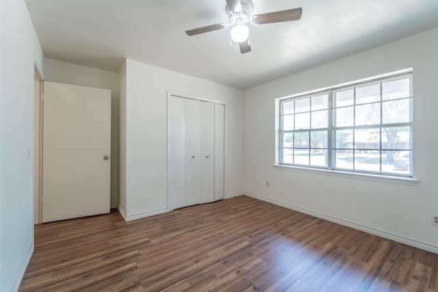 unfurnished bedroom with ceiling fan, wood-type flooring, and a closet