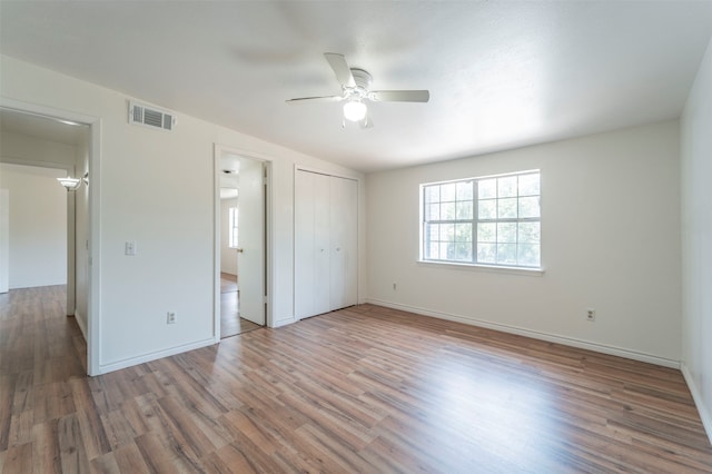 unfurnished bedroom featuring a closet, hardwood / wood-style floors, and ceiling fan