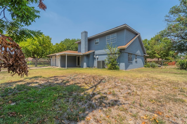 rear view of house with central AC and a yard