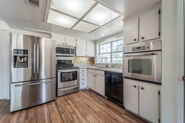 kitchen with decorative backsplash, dark hardwood / wood-style floors, appliances with stainless steel finishes, white cabinets, and sink