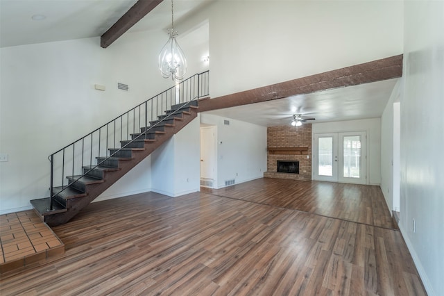 unfurnished living room with beamed ceiling, a fireplace, hardwood / wood-style floors, and ceiling fan with notable chandelier