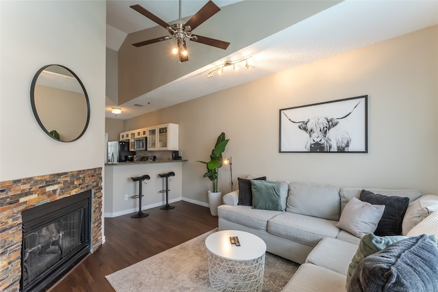 living room with ceiling fan, dark hardwood / wood-style flooring, a fireplace, and vaulted ceiling