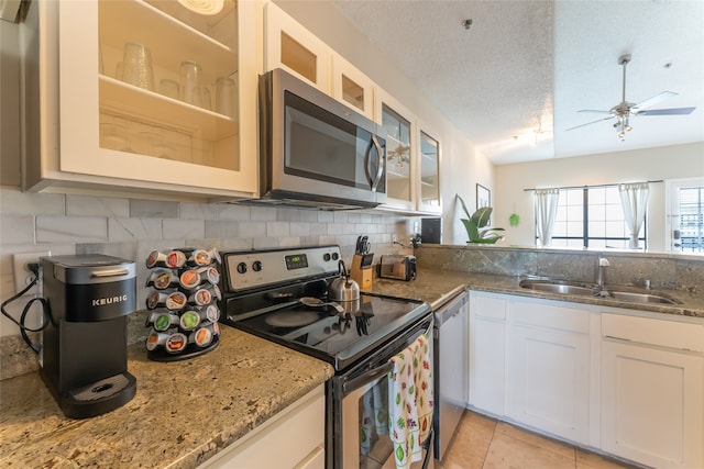 kitchen featuring ceiling fan, sink, stainless steel appliances, and white cabinetry