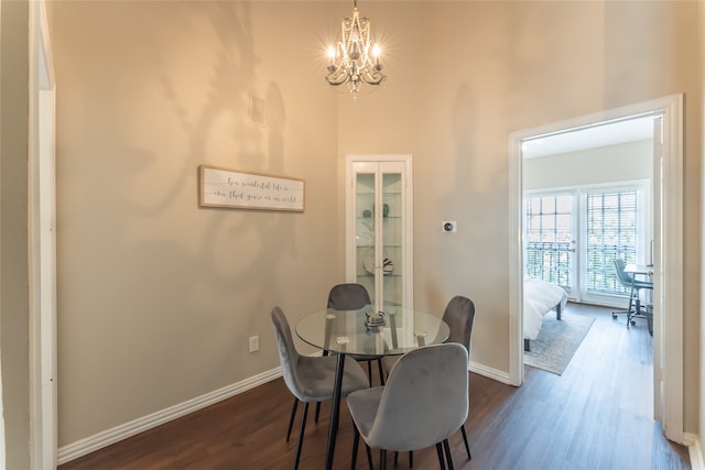 dining space with a towering ceiling, hardwood / wood-style floors, and a chandelier