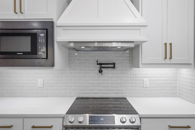 kitchen with decorative backsplash, white cabinets, and stainless steel appliances