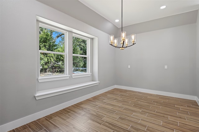 unfurnished room with a notable chandelier, wood-type flooring, and a healthy amount of sunlight