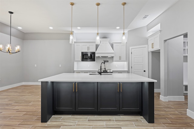 kitchen featuring a large island, decorative light fixtures, backsplash, black microwave, and sink