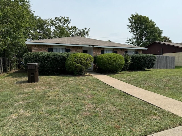 ranch-style house with a front yard, brick siding, and fence