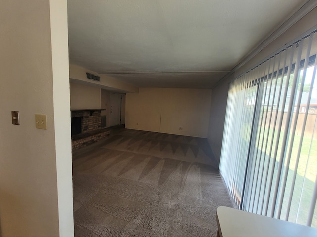 unfurnished living room featuring a brick fireplace and carpet floors