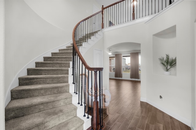 stairway featuring wood-type flooring and a towering ceiling