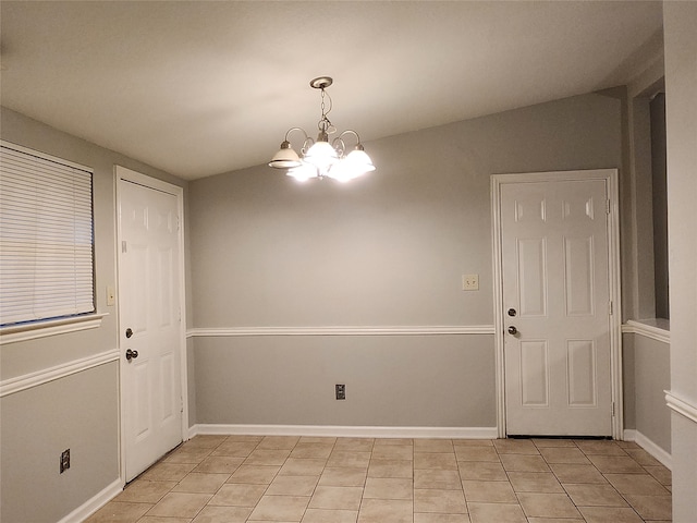 tiled spare room with vaulted ceiling and an inviting chandelier