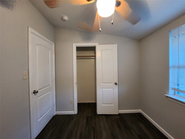 unfurnished bedroom featuring dark wood-type flooring, vaulted ceiling, ceiling fan, and a closet