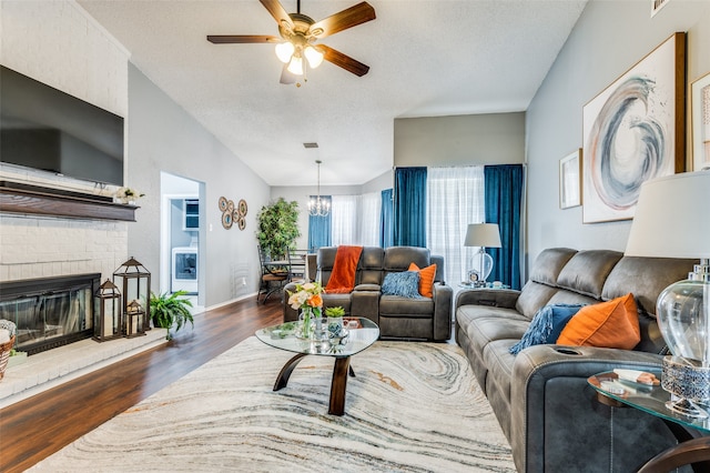 living room featuring a textured ceiling, a fireplace, dark wood-type flooring, and ceiling fan with notable chandelier