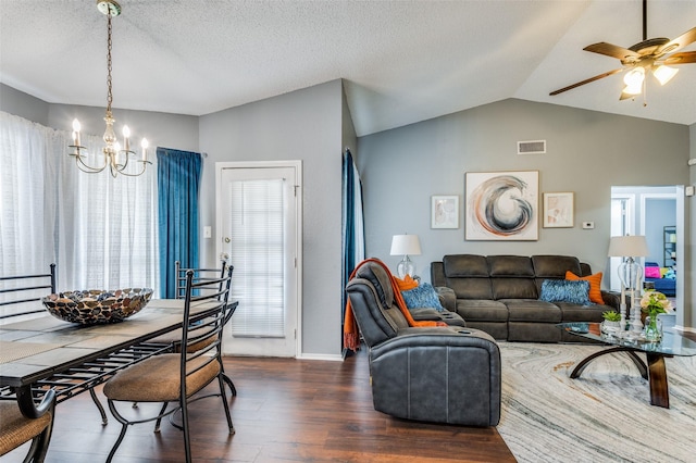 living area featuring vaulted ceiling, dark wood-style flooring, ceiling fan with notable chandelier, and a textured ceiling