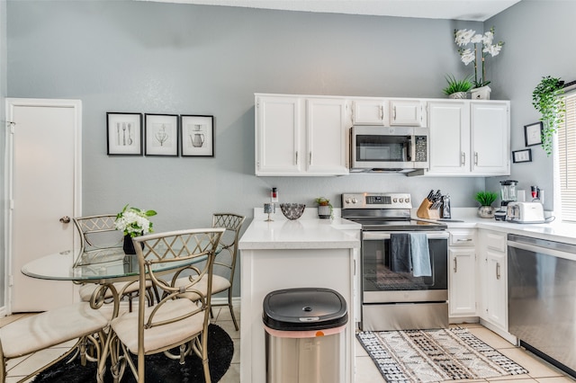 kitchen with appliances with stainless steel finishes, white cabinetry, and light tile patterned floors