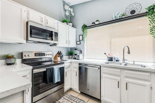 kitchen with sink, stainless steel appliances, white cabinetry, and light tile patterned floors