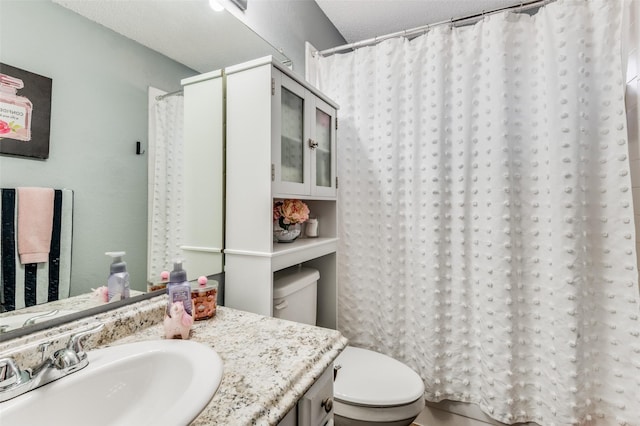 bathroom with curtained shower, vanity, and toilet