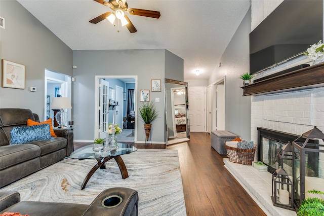 living room featuring ceiling fan, hardwood / wood-style floors, and a brick fireplace