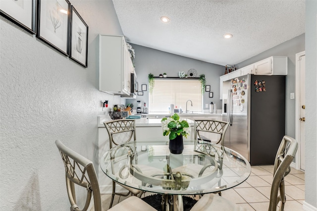 dining space featuring light tile patterned floors, recessed lighting, a textured wall, vaulted ceiling, and a textured ceiling