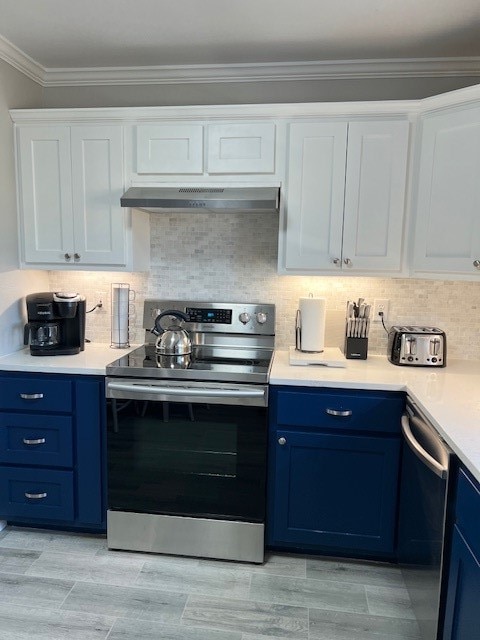 kitchen with blue cabinetry, crown molding, appliances with stainless steel finishes, white cabinets, and backsplash