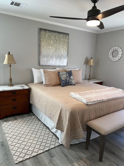 bedroom featuring hardwood / wood-style floors, crown molding, and ceiling fan