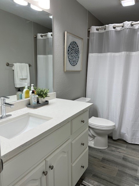 bathroom with toilet, vanity, and hardwood / wood-style floors