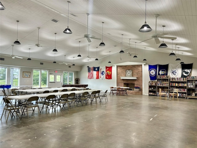 dining space with ceiling fan, high vaulted ceiling, a fireplace, and concrete flooring