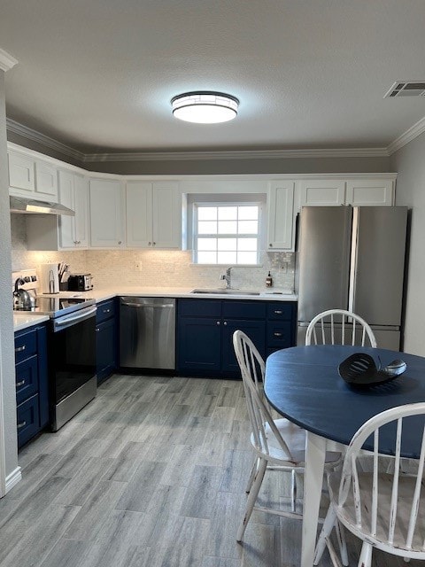 kitchen with blue cabinets, appliances with stainless steel finishes, sink, and white cabinets