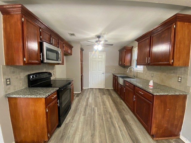 kitchen featuring light hardwood / wood-style flooring, black electric range oven, light stone countertops, ceiling fan, and decorative backsplash