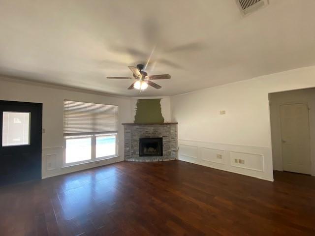 unfurnished living room featuring ceiling fan, a fireplace, hardwood / wood-style floors, and crown molding