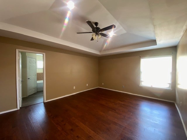 spare room with ceiling fan, a raised ceiling, and dark hardwood / wood-style floors