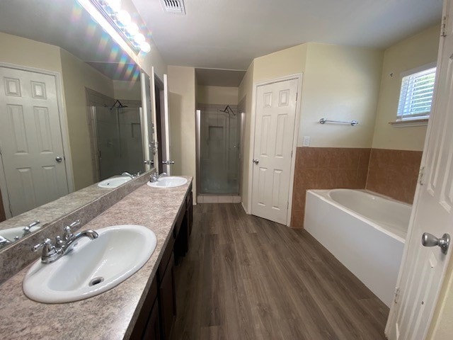 bathroom featuring dual bowl vanity, wood-type flooring, and independent shower and bath