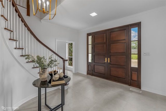 foyer with light tile patterned floors, a healthy amount of sunlight, ornamental molding, and an inviting chandelier