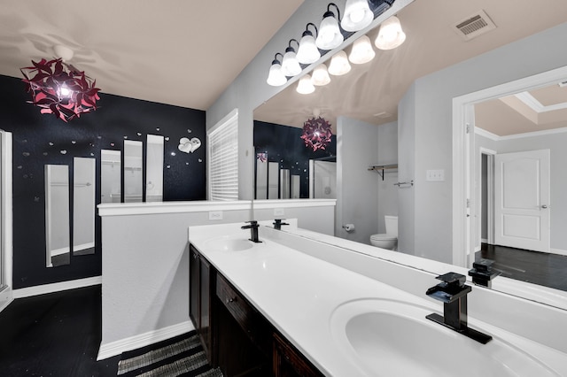 bathroom with double vanity, toilet, and ornamental molding