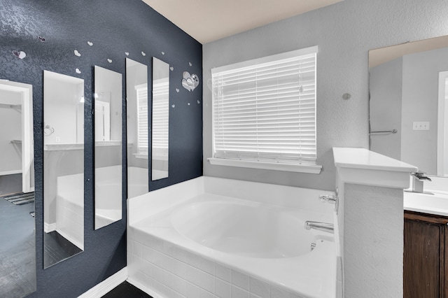 bathroom featuring a relaxing tiled tub and vanity