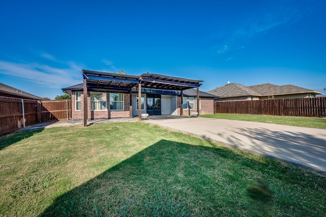 back of property with a pergola, a lawn, and a patio area