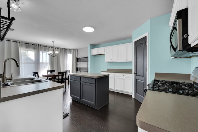 kitchen featuring dark hardwood / wood-style flooring, an inviting chandelier, white cabinets, sink, and decorative light fixtures