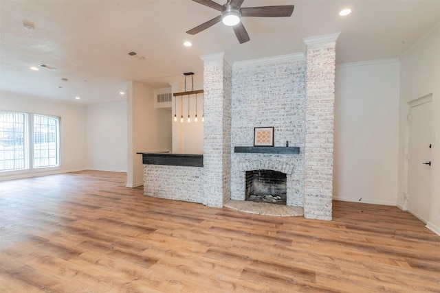 unfurnished living room featuring ceiling fan, light wood-type flooring, crown molding, and a brick fireplace