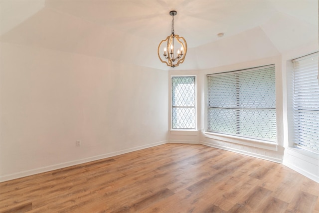 spare room featuring hardwood / wood-style floors and an inviting chandelier