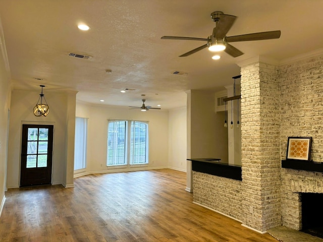 unfurnished living room featuring hardwood / wood-style flooring, ceiling fan, a fireplace, and a textured ceiling