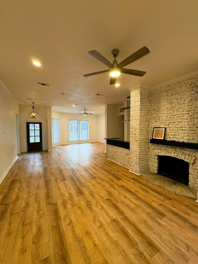 unfurnished living room featuring light hardwood / wood-style floors, a stone fireplace, and ornamental molding