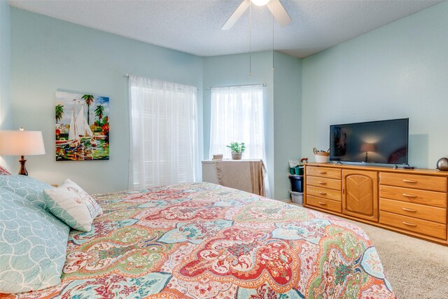 bedroom with ceiling fan, a textured ceiling, and carpet floors