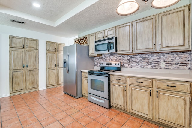 kitchen with appliances with stainless steel finishes, light tile patterned flooring, tasteful backsplash, and a textured ceiling