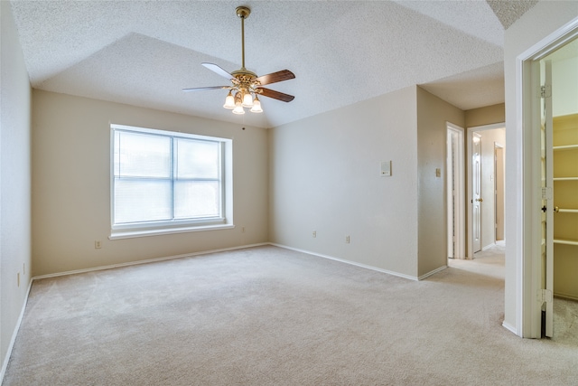 carpeted spare room with ceiling fan, a textured ceiling, and lofted ceiling