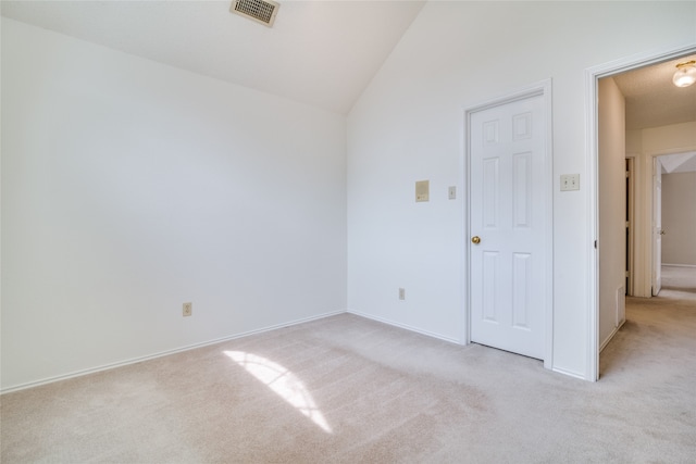 empty room featuring vaulted ceiling and light colored carpet