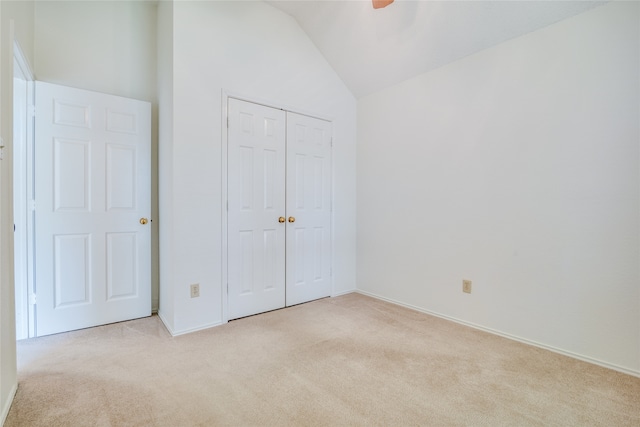 unfurnished bedroom featuring ceiling fan, high vaulted ceiling, light carpet, and a closet