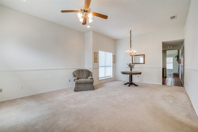 unfurnished room with ceiling fan with notable chandelier and light carpet