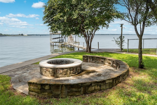 exterior space with a boat dock, a water view, and an outdoor fire pit