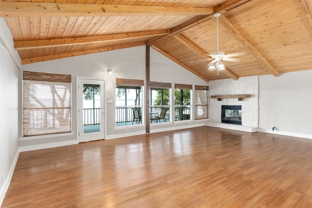 unfurnished living room featuring light hardwood / wood-style flooring, beamed ceiling, a stone fireplace, and wooden ceiling